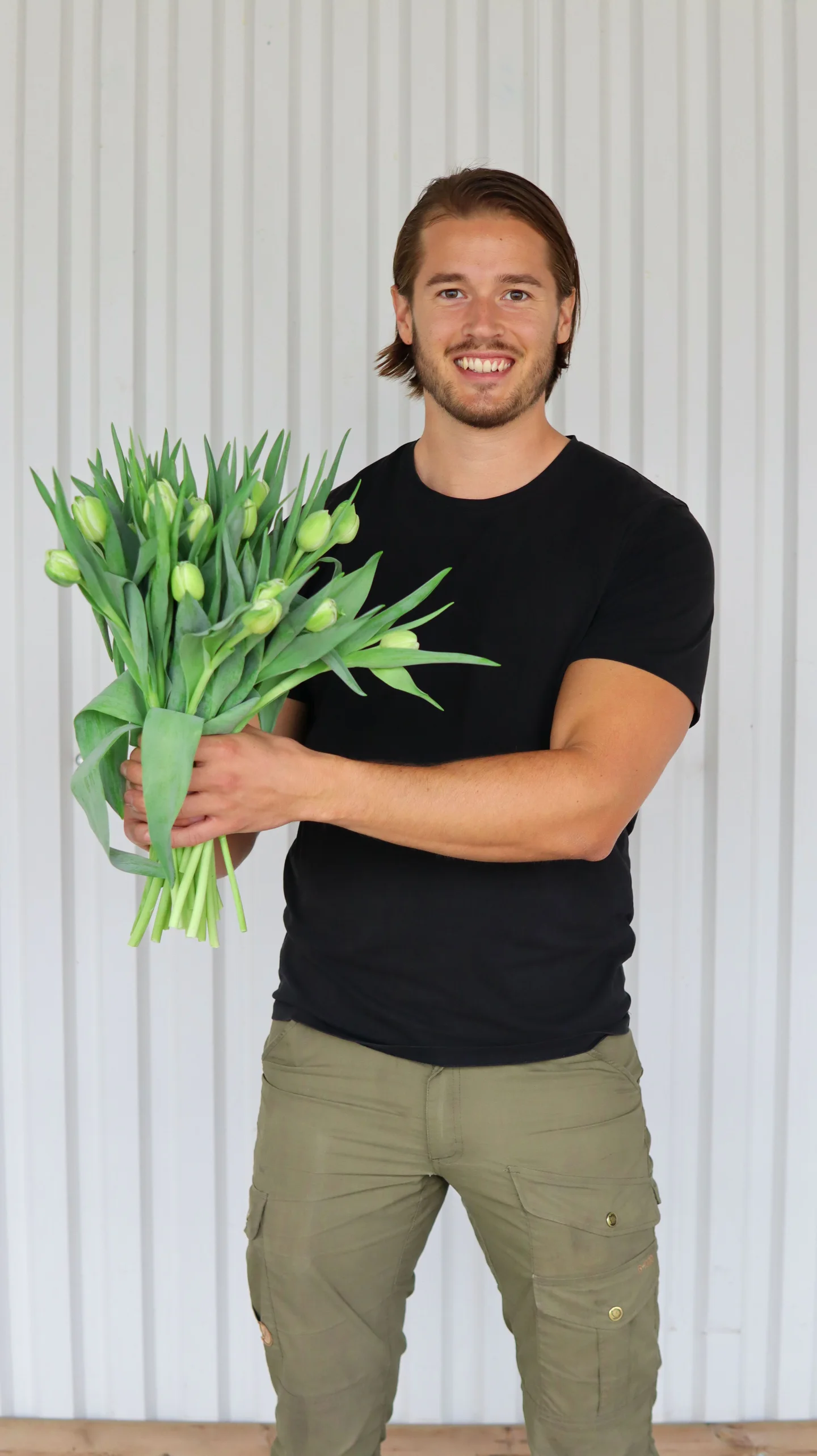 Jacob Sagmeister holding a bouquet of tulips and smiling at the camera.